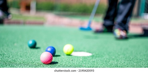 Mini Golf Game With Several Colored Balls In The Way Of A Putter Lined Up.