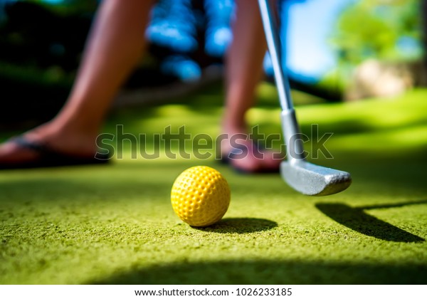 Mini Golf yellow\
ball with a bat at sunset