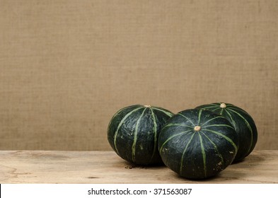 Mini green pumpkin on old wood with blurred brown sack background