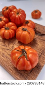 Mini Heirloom Tomatoes on Rustic Wooden Cutting Board. Fresh organic heirloom mini tomatoes arranged on a rustic wooden cutting board over a clean white background. Top view with copy space, ideal for healthy food, farm-to-table, agriculture, cooking ingredients, and fresh produce concepts.