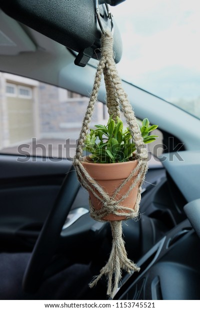 A mini jute twine\
macrame plant hanger with a ceramic pot. This hanger has a faux\
(Fake) plant inside of it. This hanger is made as a car decoration\
/ charm. Side View.