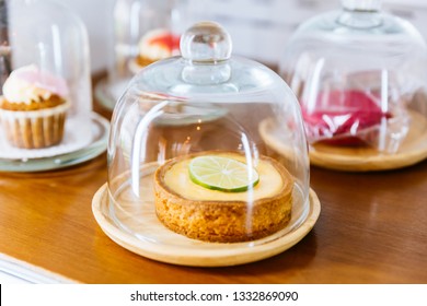 Mini Key Lime Pie Topping With Slice Of Lime In Wooden Plate And Cover With Glass Cloche.