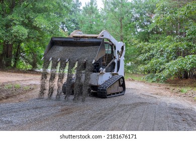 The Mini Loader Bobcat Tractor Moves And Unloads Gravel On The Old Road Reconstruction Site