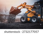 Mini loader with bucket. Mini loader is preparing the terrain. Mini wheel loader is spreading the stone onto the work surface.