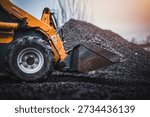 Mini loader with bucket. Mini loader is preparing the terrain. Mini wheel loader is spreading the stone onto the work surface.