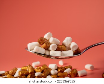 Mini marshmallows on a pink background. Marshmallow gold and white. Close-up.