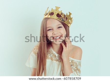 Mini Miss. Young happy girl with a cute smiling laughing wearing a crown and a white dress on Holiday looking at you camera isolated green background 