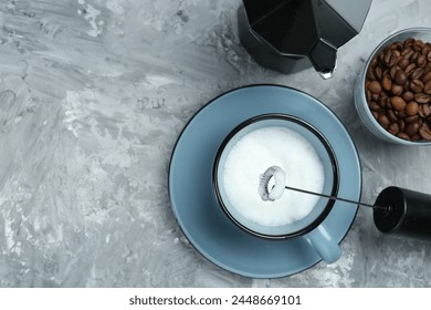 Mini mixer (milk frother), whipped milk in cup, coffee beans and moka pot on grey textured table, flat lay. Space for text - Powered by Shutterstock