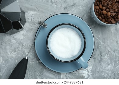 Mini mixer (milk frother), whipped milk in cup, coffee beans and moka pot on grey textured table, flat lay - Powered by Shutterstock