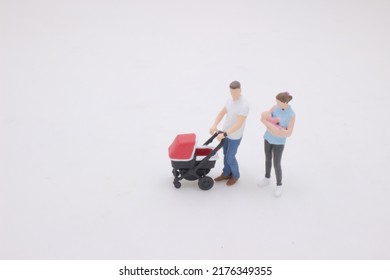 The Mini Of Mother And Father Walking Outdoors And Pushing Baby In Pram