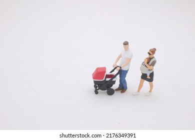 The Mini Of Mother And Father Walking Outdoors And Pushing Baby In Pram