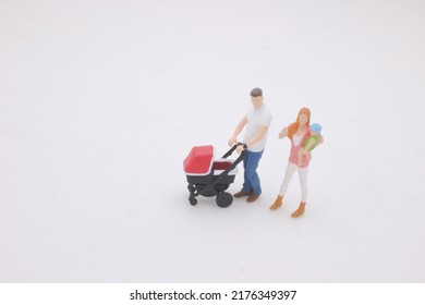 The Mini Of Mother And Father Walking Outdoors And Pushing Baby In Pram