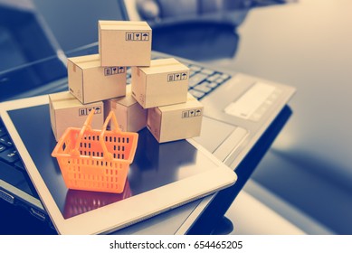 Mini orange shopping basket on a smart device and a laptop with boxes. Concept of shopping that client can buy or purchase goods or products from websites worldwide via internet by just a few clicks. - Shutterstock ID 654465205