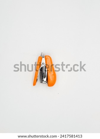 Mini orange stepler on white background