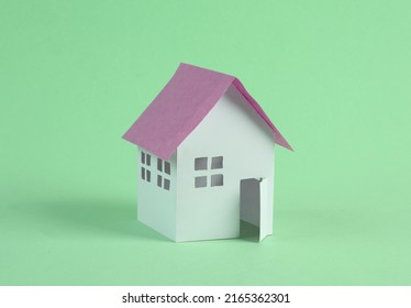 Mini paper house figurine on green background 