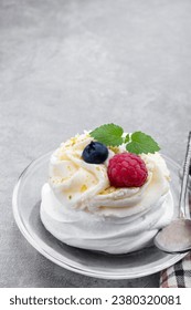 Mini  Pavlova meringue nest with berries and whipped cream on gray background 