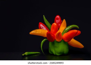 Mini peppers and chili peppers in a vase of bell peppers in the form of a bouquet with a  large shot a black background.Edible composition.