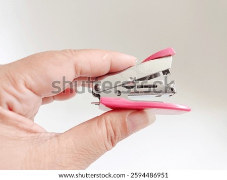 Mini pink stepler isolated on white background. Hand holding steplest