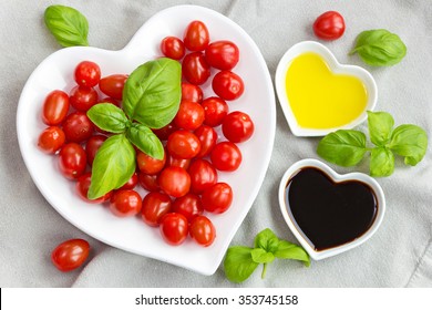 Mini plum tomatoes with fresh basil and oil and vinegar in heart shaped bowls for a lovely salad