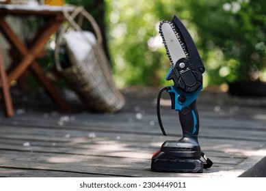 mini portable electric chain saw on summer garden background  - Shutterstock ID 2304449011