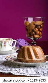 Mini Pound Cake - Almond Lemon Drizzle On Old Pictures Coffee Cup, Side Plate On Lace And Glass Full Of Almonds And Hazelnuts, Purple Background