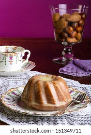 Mini Pound Cake - Almond Lemon Drizzle On Old Pictures Coffee Cup, Side Plate On Lace And Glass Full Of Almonds And Hazelnuts, Purple Background