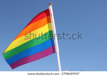 Mini rainbow pride flag waves in the blue sky 