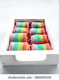 Mini Rainbow Roll Cake In White Wooden Tray.