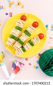 Mini Shaped Sandwich Kabobs With Cheese, Ham, Cherry Tomato, Cucumber And Wholemeal Bread Over Yellow Plate On Pink Background With Party Decor, Space For Text. Kids Party Finger Snacks Food Concept.