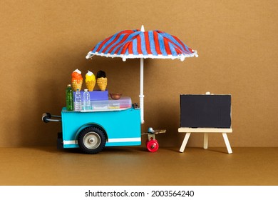 Mini shop Ice cream cart with blue red umbrella. Assortment of ice cream empty menu black chalkboard. Summer vacation concept. brown background.