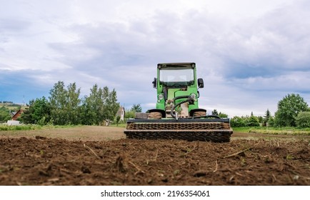 Mini Skid Steer Loader Clear The Construction Site. Land Work By The Territory Improvement. Small Tractor With A Rotary Cultivator Attachment And Ground Leveler For Moving Soil. Agriculture Machine.