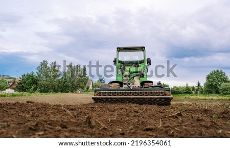 Mini skid steer loader clear the construction site. Land work by the territory improvement. Small tractor with a rotary cultivator attachment and ground leveler for moving soil. Agriculture machine.
