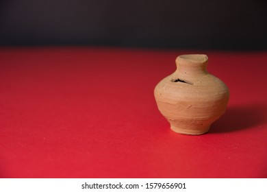Mini small money saving mud box on a red floor and black background traditional money saving box