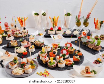 Mini snacks on a white background. Cold appetizer. On a black serving board. Snacks for public catering . Catering. Buffet table. Catering. - Shutterstock ID 2153183357