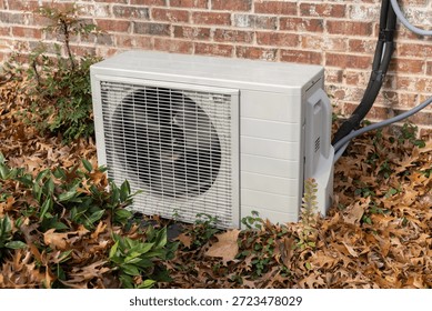 Mini split air conditioning unit outside surrounded by fall leaves