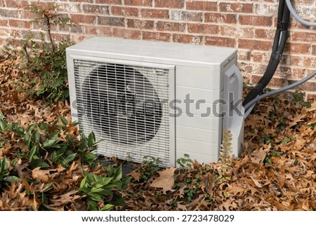 Mini split air conditioning unit outside surrounded by fall leaves