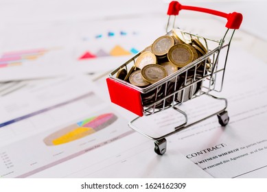 Mini Supermarket Cart Full Of Coins With Data Chart And Profits In Commerce.