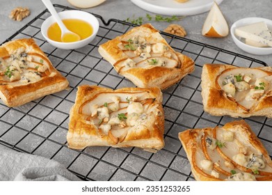 Mini tarts with puff pastry, pieces of pear, blue cheese, walnuts and honey on a concrete background. Top view - Powered by Shutterstock