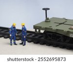 Mini toy of action figure at outdoor with blurred background. Toy photography concept design. Minifigure of engineer character and train at railtrack.