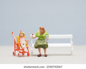 Mini toy of action figure at table with blurred background. Toy photography concept design. Minifigure of parent with baby at garden bench. - Powered by Shutterstock