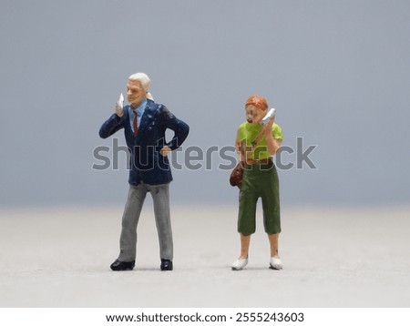 Mini toy of action figure at table with blurred background. Toy photography concept design. Minifigure of people character calling with his mobile phone.
