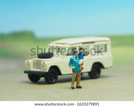 Mini toy of action figure at table with blurred background. Miniature diorama photography concept design. MInifigure of father and son character with car at outdoor. Traveling, holiday and vacation.