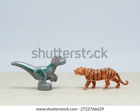 Mini toy of action figure at table with blur background. Miniature photography concept design. Minifigure of Dinosaurs and Tiger character. Animal at wildlife.