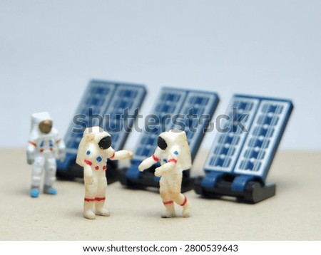 Mini toy of action figure at table with blurred background. Miniature photography concept design. Minifigure of astronaut character with solar panel at new planet.