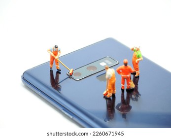 Mini toy and unfocus smartphone at table with white background. Cleaning crew at cellphone body. - Powered by Shutterstock