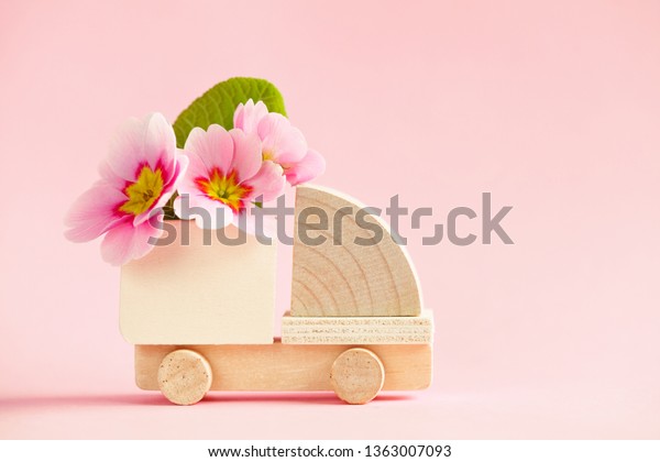 mini toy wooden cargo truck model with\
beautiful fresh spring flowers isolated on pastel pink background,\
flower delivery, eco-friendly car\
concept