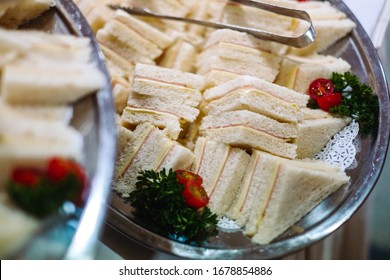 Mini triangular cheese and ham sandwich platter with metal tongs at the side