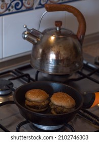 Mini Veggie Hamburgers Being Heated Up In A Frying Pan And Kettle In The Background.