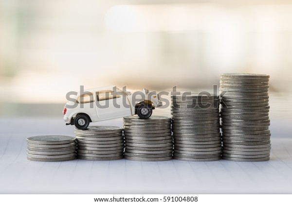Mini white car model on stack of coins.\
Saving, Finance, Loan and leasing\
Concept.