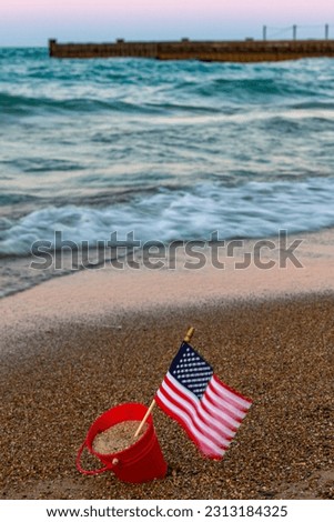 Miniature American Flag sits in a bucket on a beach at Lake Michigan in Chicago